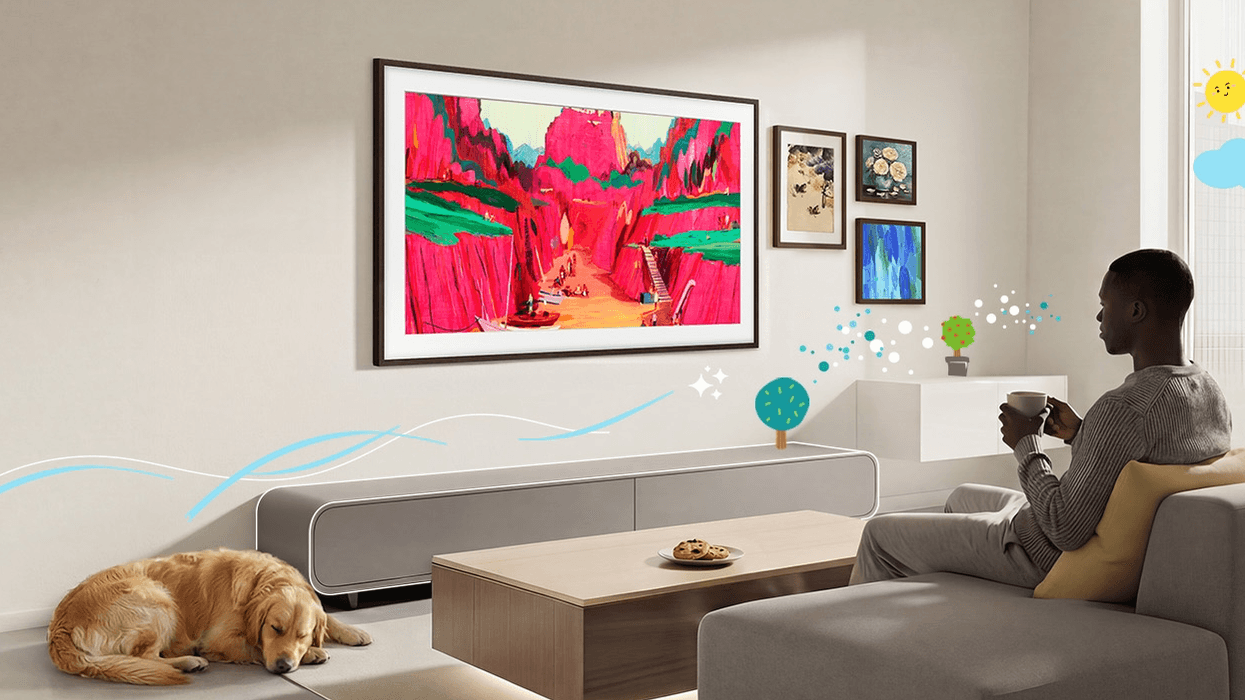 Man sitting with a cup of tea on the sofa watching artwork on the frame tv from samsung