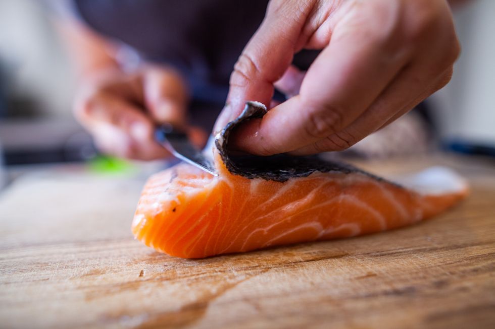 Man skinning his salmon on a chopping board