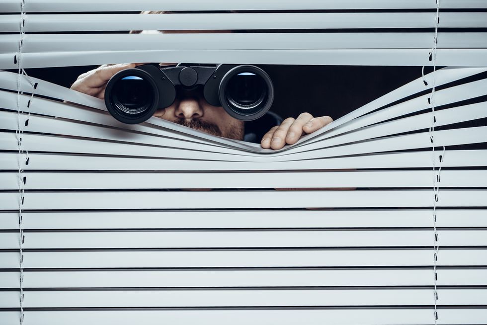 Man spying through window blinds