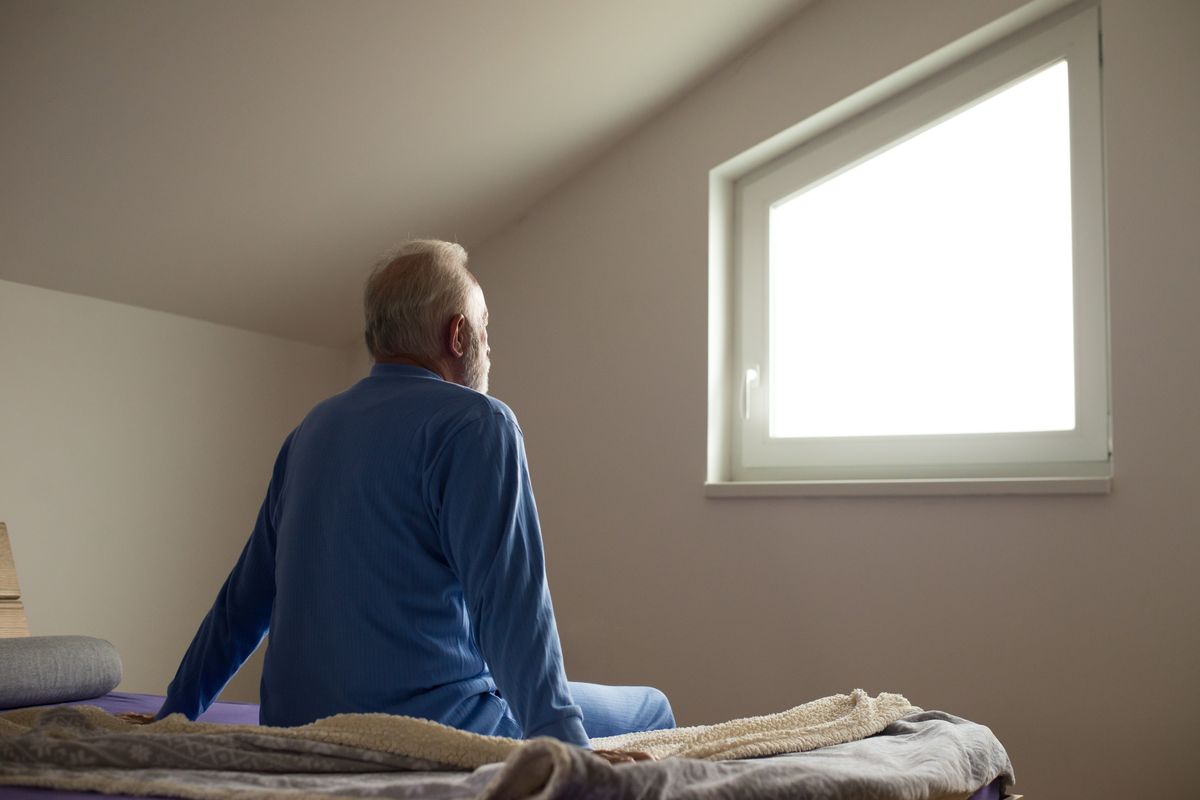 Man staring out the window after waking up in the morning