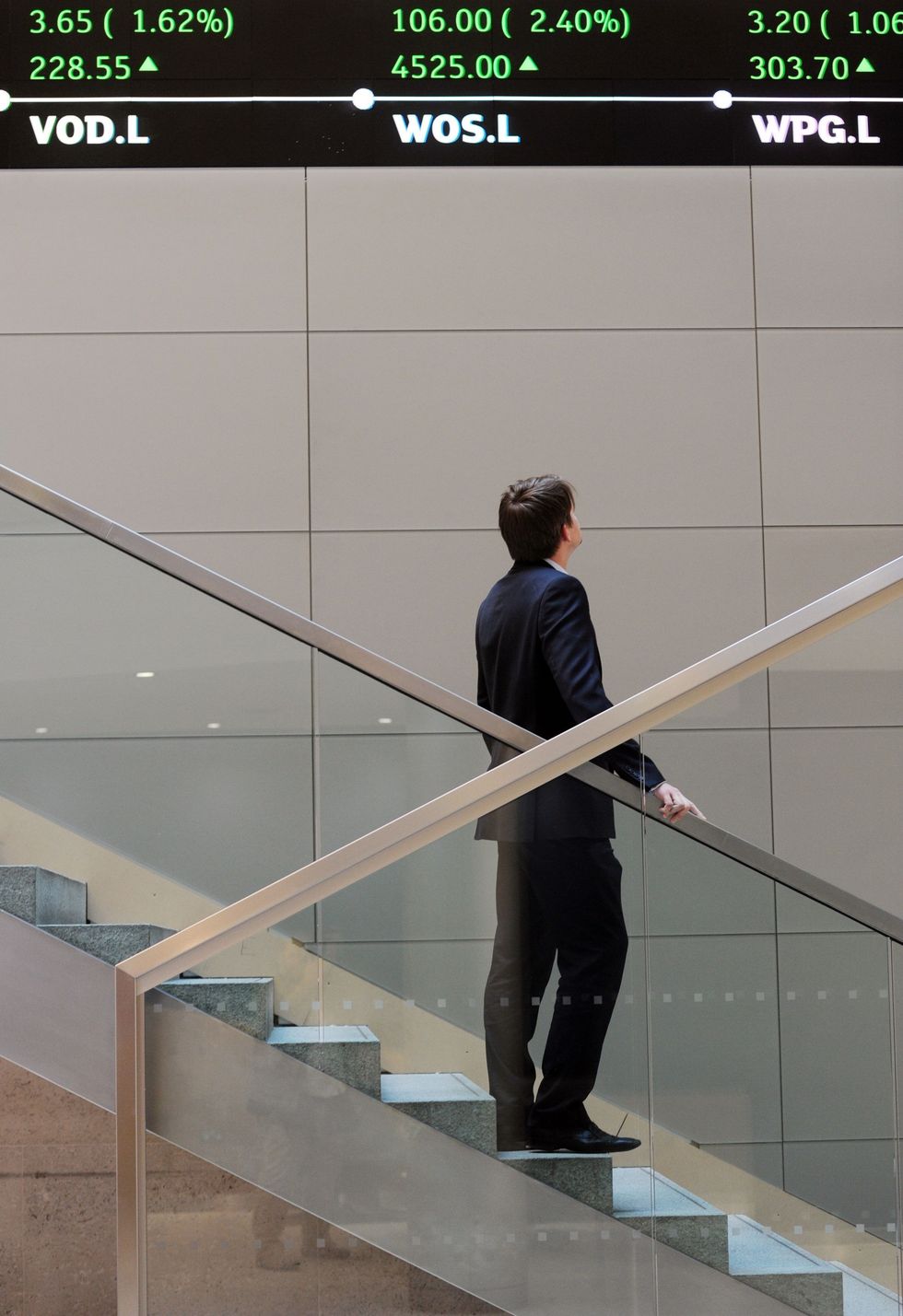 Man staring up at electronic ticker tape showing the FTSE 100