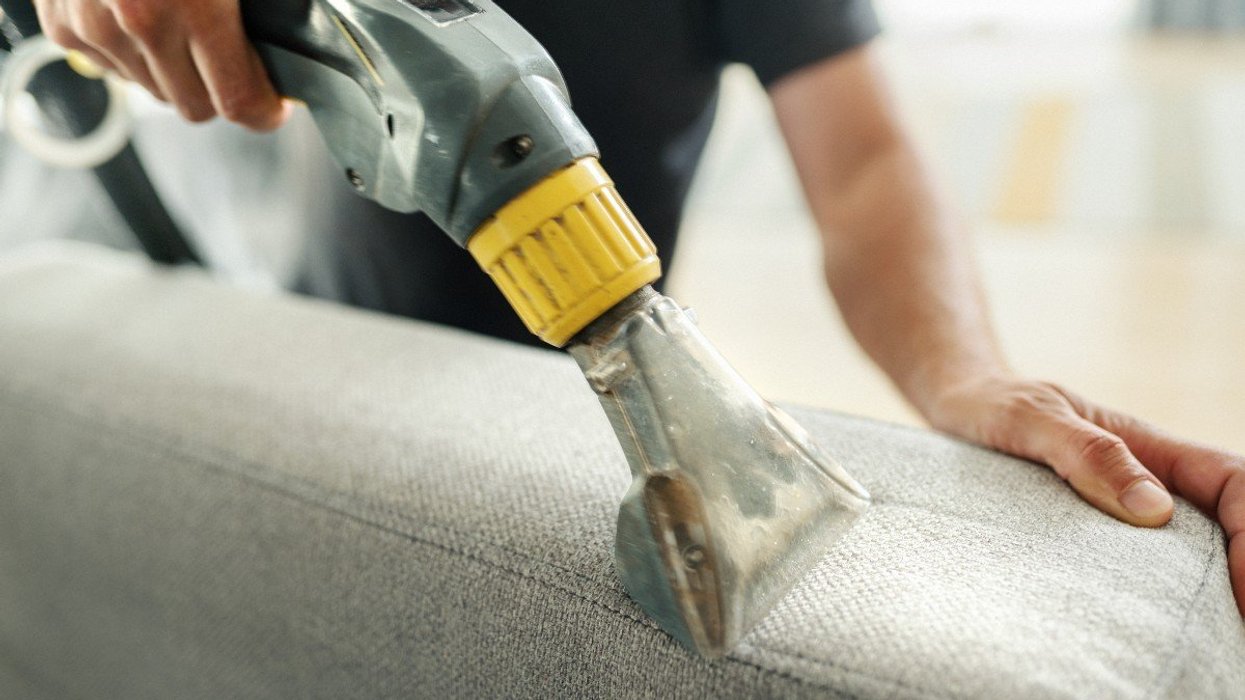 Man using vacuum cleaner on sofa