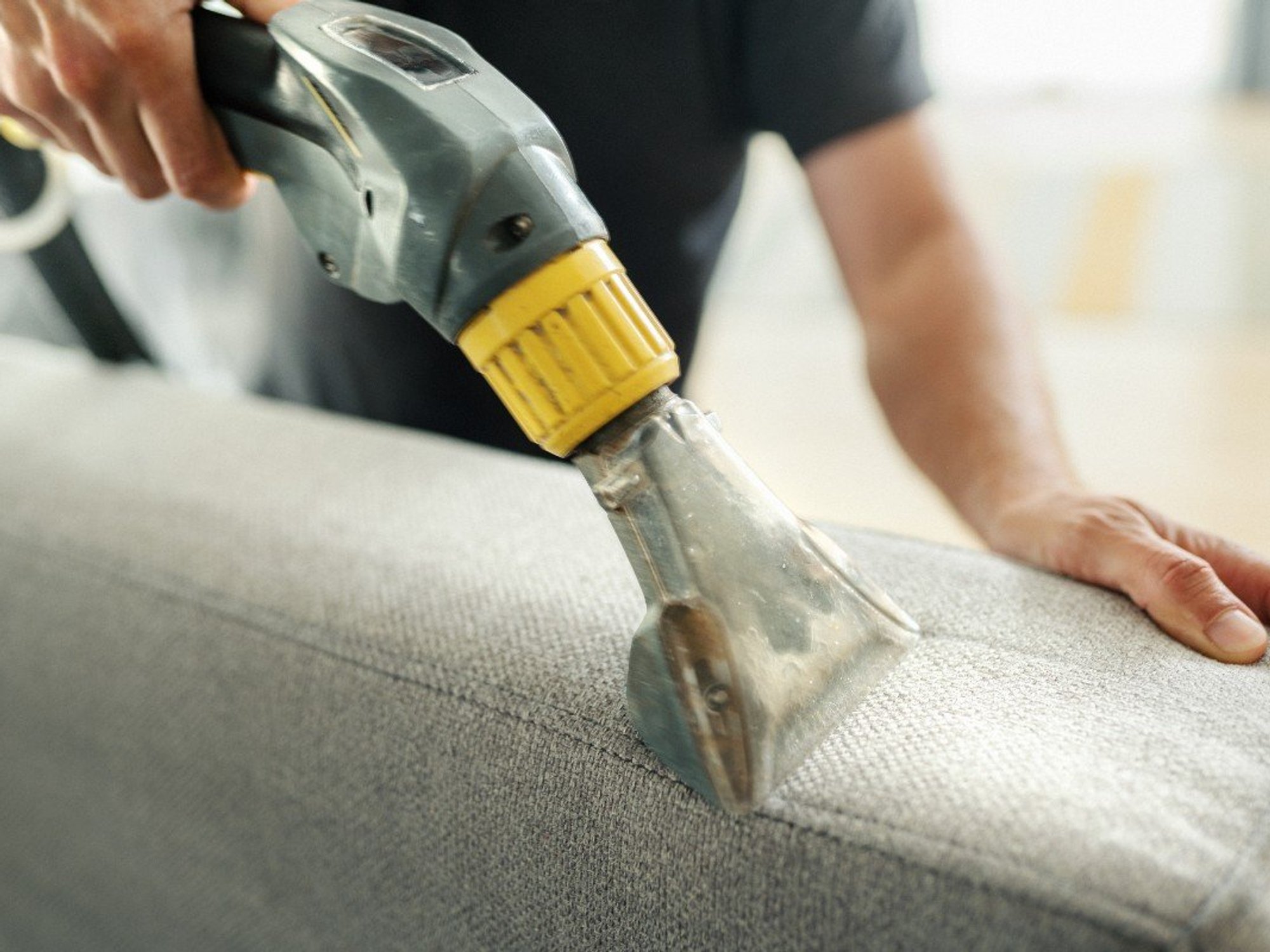 Man using vacuum cleaner on sofa