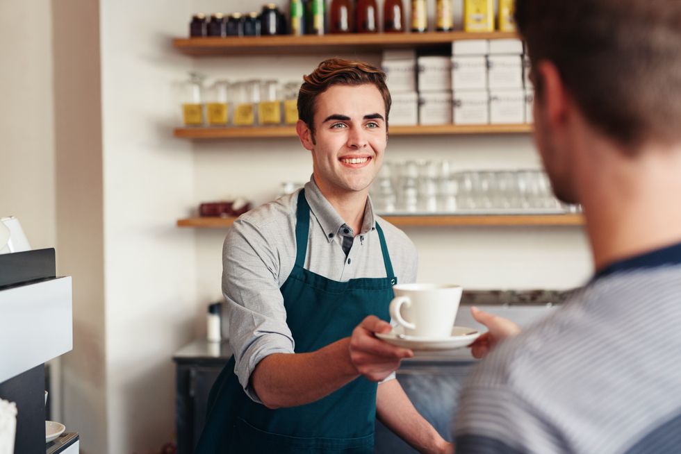 Man working at coffee shop handing someone their order