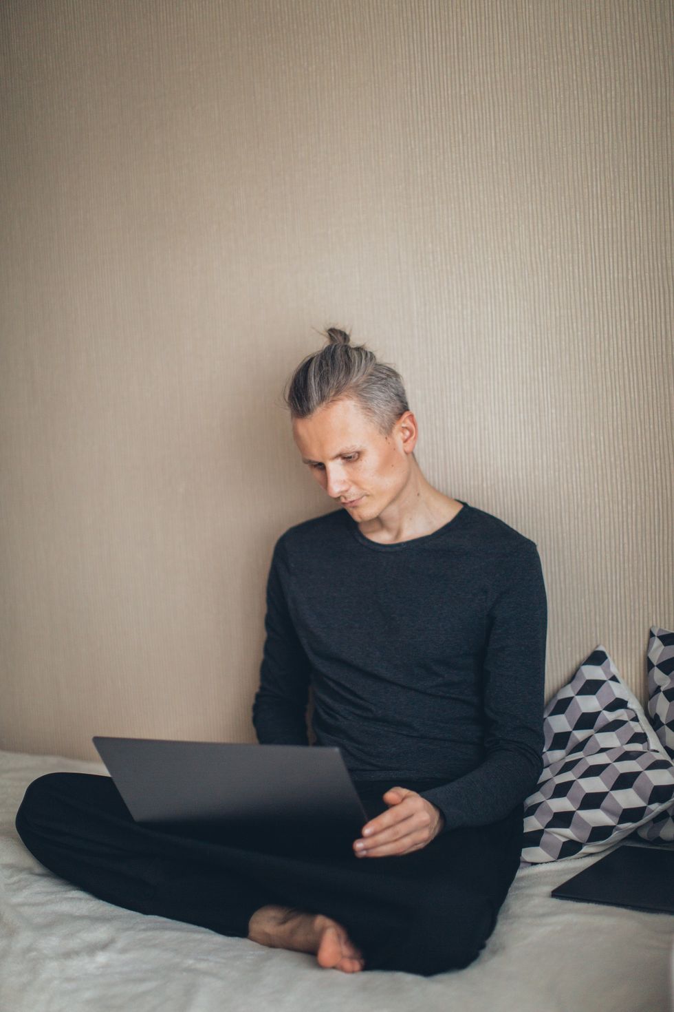 Man working on laptop on bed