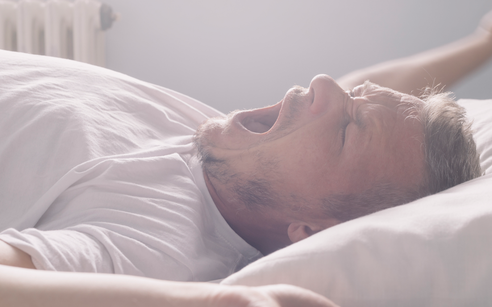 Man yawns as he wakes up in his bed