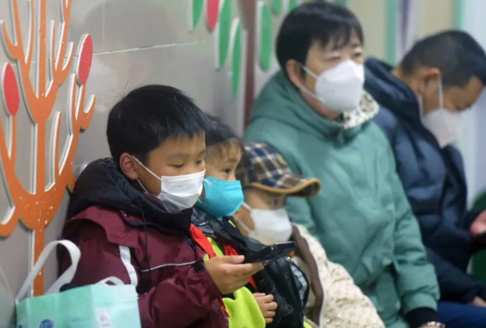 Masked children, accompanied by adults, wait to be seen by medical staff at a hospital in Hangzhou, eastern China's Zhejiang province, on January 6, 2025.