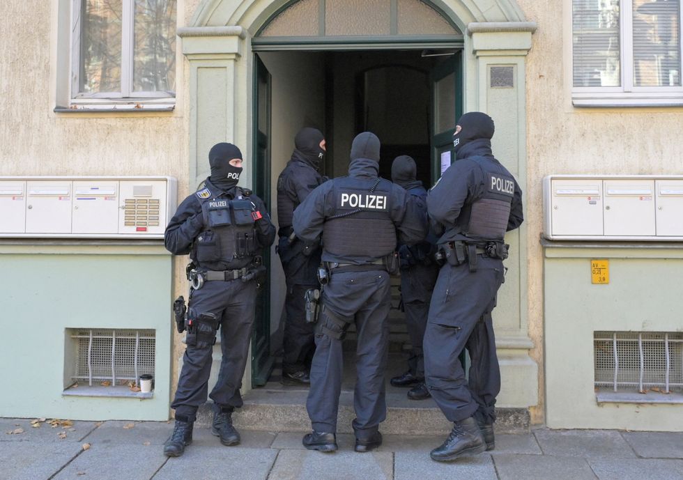 Masked German police officers guard a house