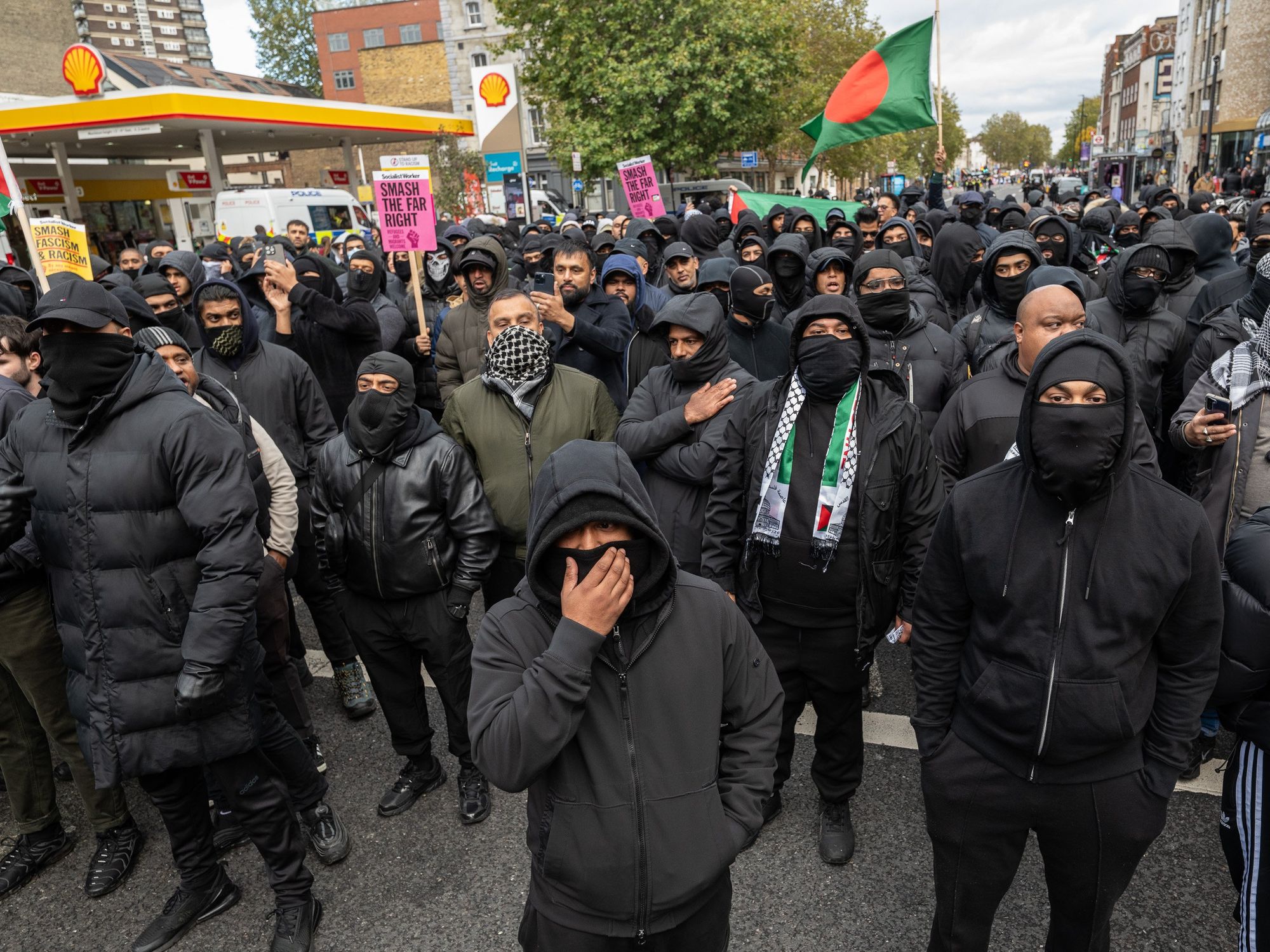 Masked men march through Whitechapel, Tower Hamlets - with one waving a Bangladeshi flag