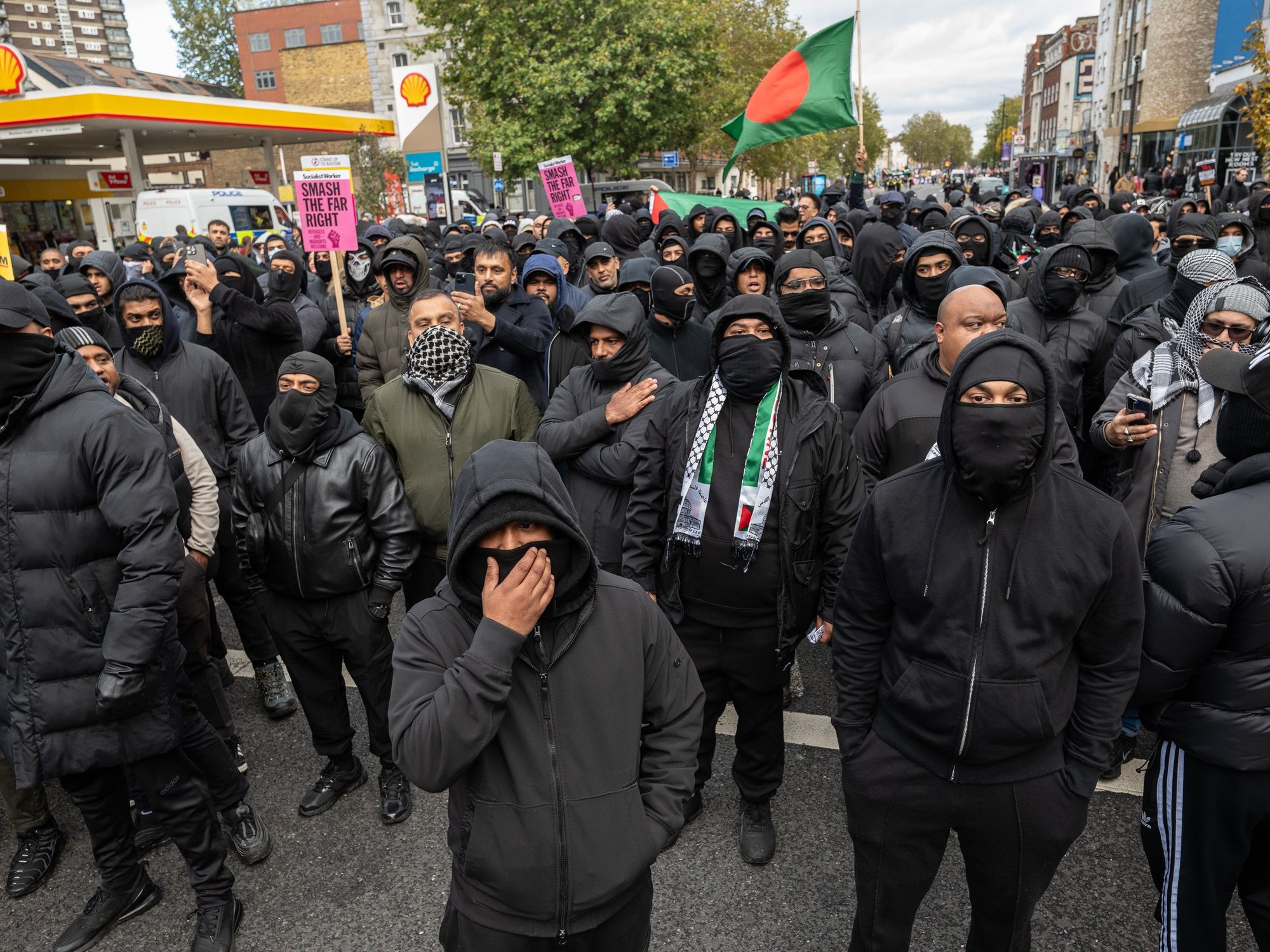 Masked men march through Whitechapel, Tower Hamlets - with one waving a Bangladeshi flag