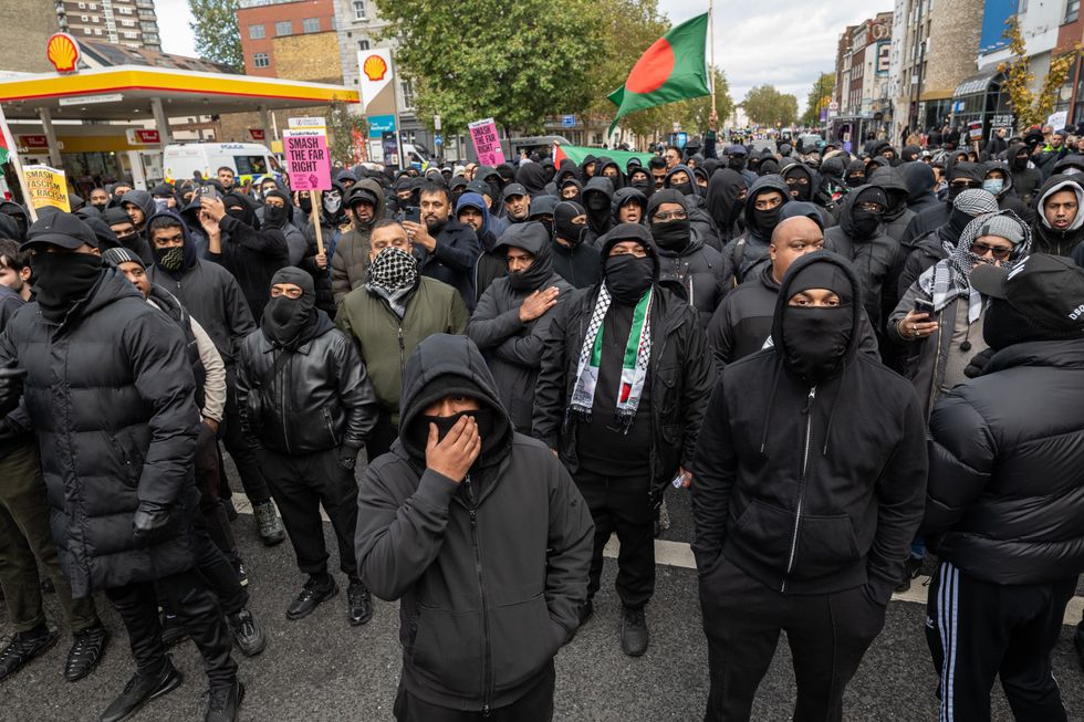 Masked men march through Whitechapel, Tower Hamlets - with one waving a Bangladeshi flag
