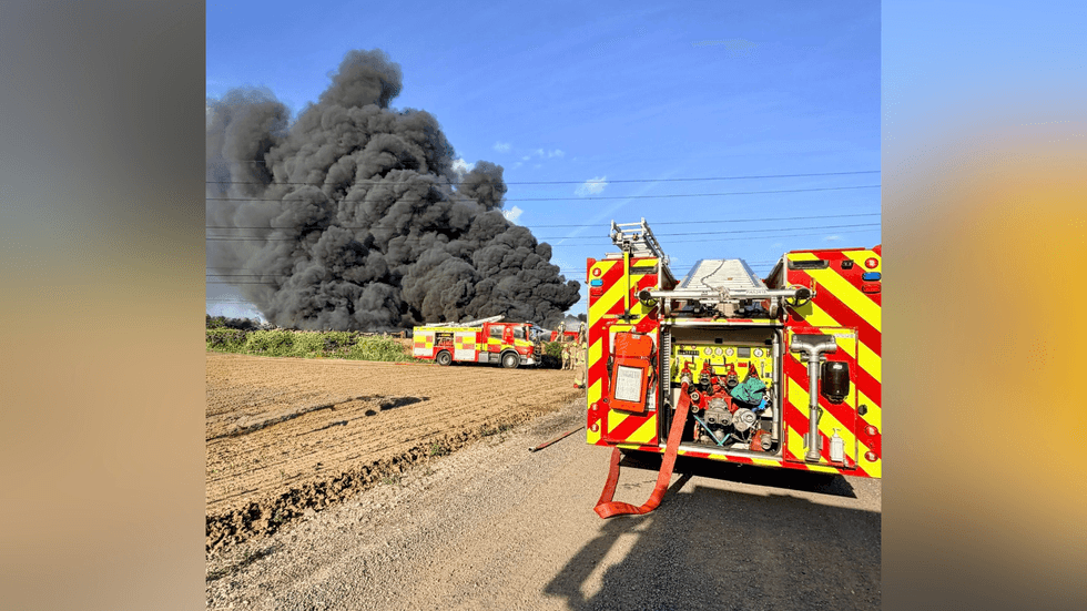 Massive smoke cloud in distance with parked up fire engines