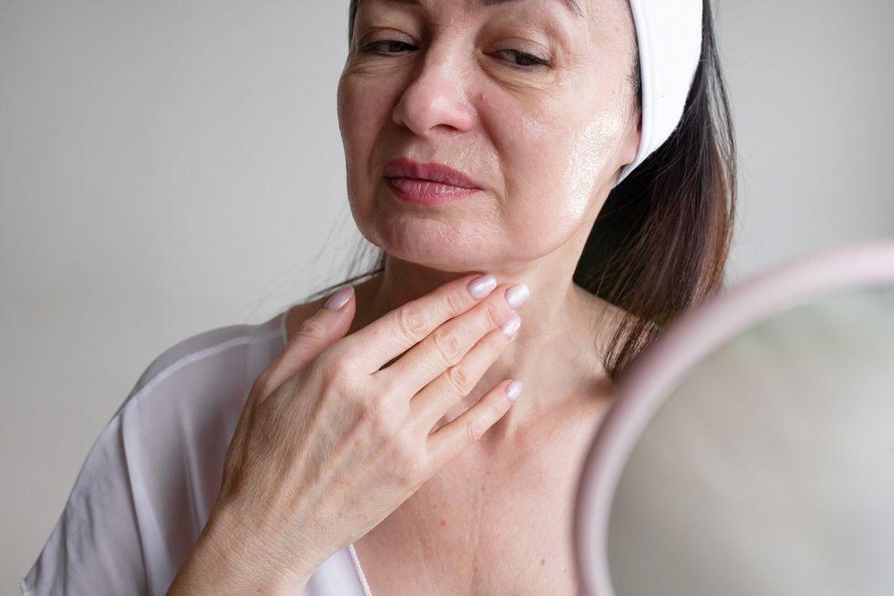 Mature woman examining her face and neck in the mirror