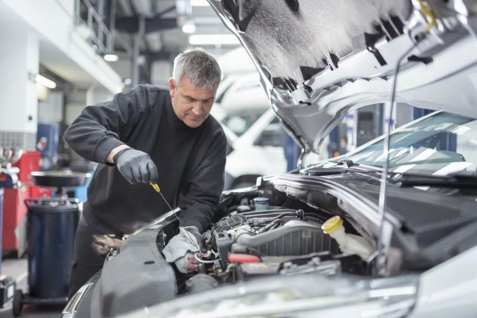 Mechanic checking oil levels of vehicle