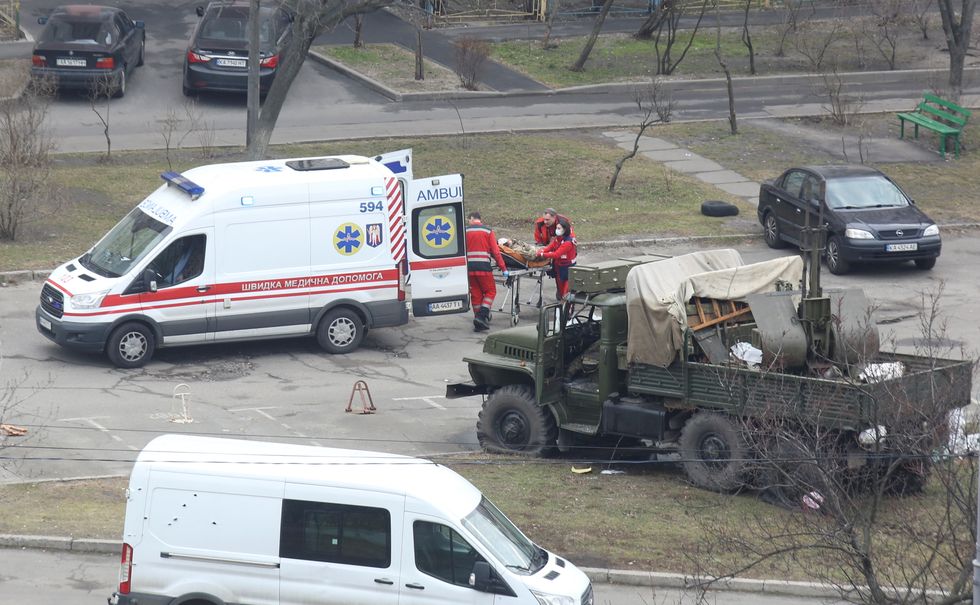 Medics transport a person wearing a military uniform into an ambulance near a damaged unidentified military truck at a residential area in Kyiv, Ukraine February 25, 2022. REUTERS/Olga Yakimovich