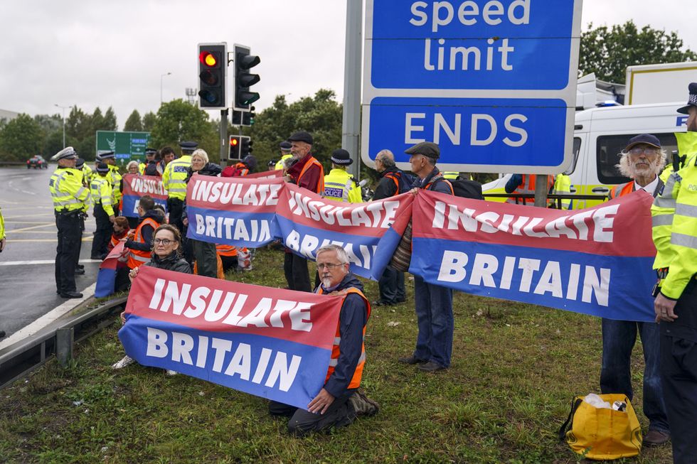 Members of Insulate Britain occupying a roundabout leading from the M25 motorway to Heathrow Airport in London. Picture date: Monday September 27, 2021.
