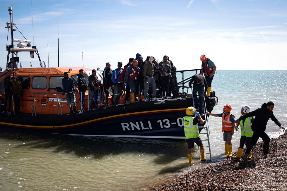 Members of Royal National Lifeboat Institution help migrants to disembark from a Royal National Lifeboat Institution (RNLI) lifeboat on the beach at Dungeness