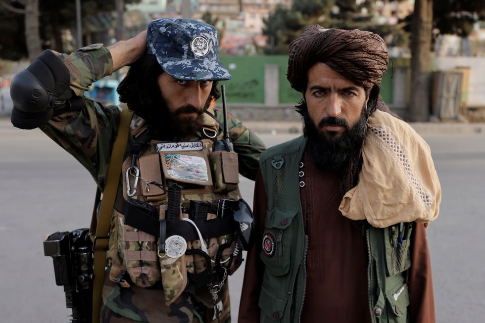 Members of Taliban forces, of which one is armed, pose at a check point after several civilians were killed in an explosion, in Kabul.
