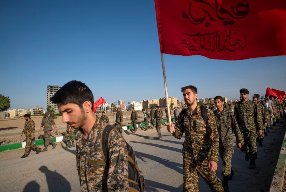 Members of the Islamic Revolutionary Guard Corps (IRGC) walk along a road to the holy mosque of Jamkaran