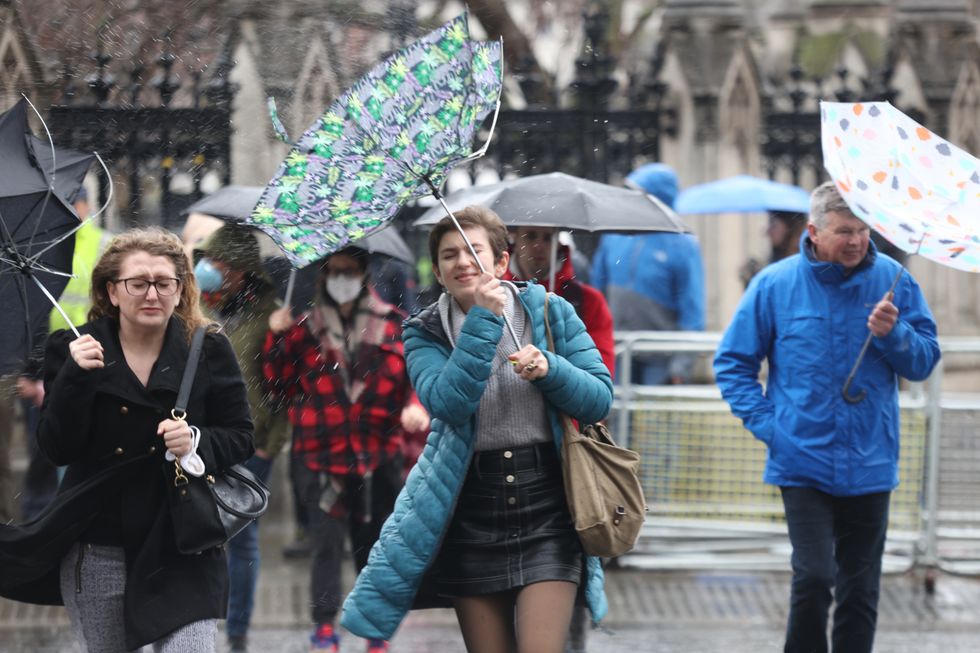 Members of the public brace the wind and wet weather in Westminster central London following Storm Eunice.