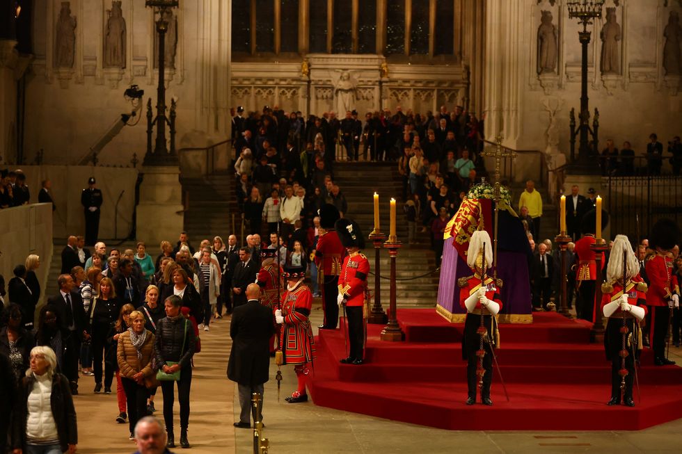 Members of the public file past the coffin of Queen Elizabeth II, draped in the Royal Standard with the Imperial State Crown and the Sovereign's orb and sceptre, lying in state on the catafalque in Westminster Hall, at the Palace of Westminster, London, ahead of her funeral on Monday. Picture date: Friday September 16, 2022.