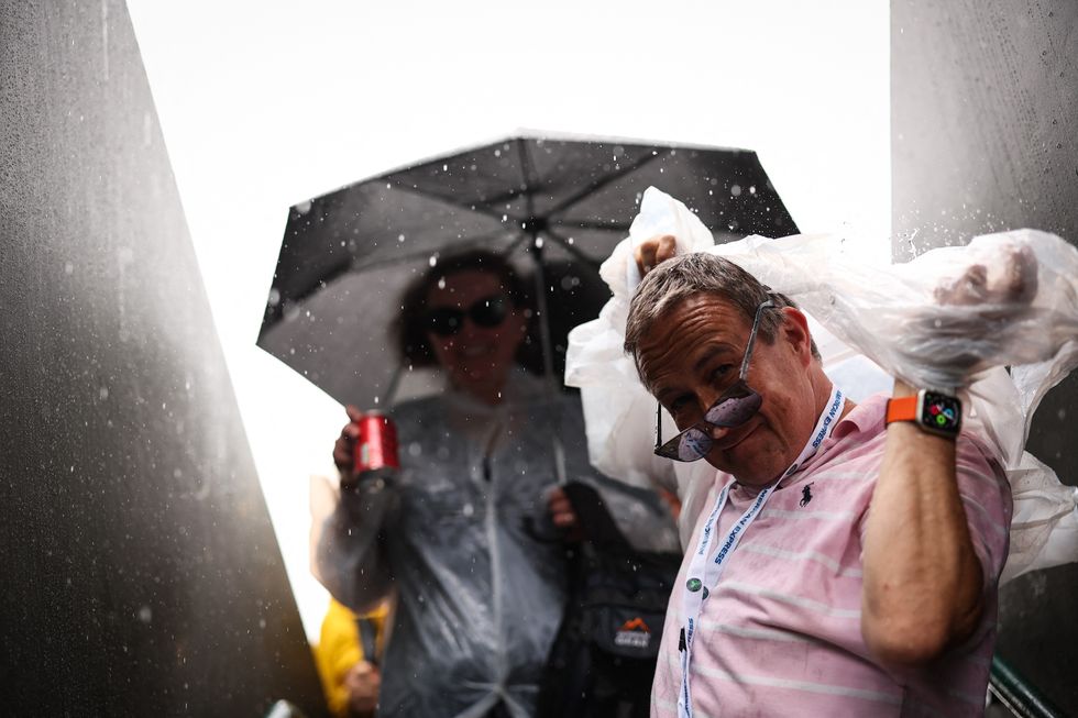 Members of the public holding umbrellas and puting on their raincoat leave court 2 as the rain starts to fall on the seventh day of the 2025 Wimbledon Championships at The All England Lawn Tennis and Croquet Club in Wimbledon