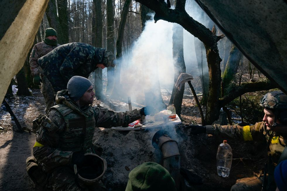 Members of the Ukrainian forces prepare food amid Russia's invasion of Ukraine, near Demydiv, Ukraine March 10, 2022. REUTERS/Maksim Levin
