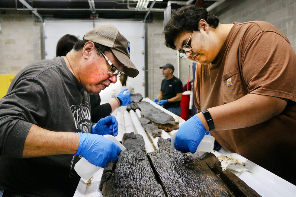 Members of the Wisconsin Historical Society work on segments of one of the ancient canoes