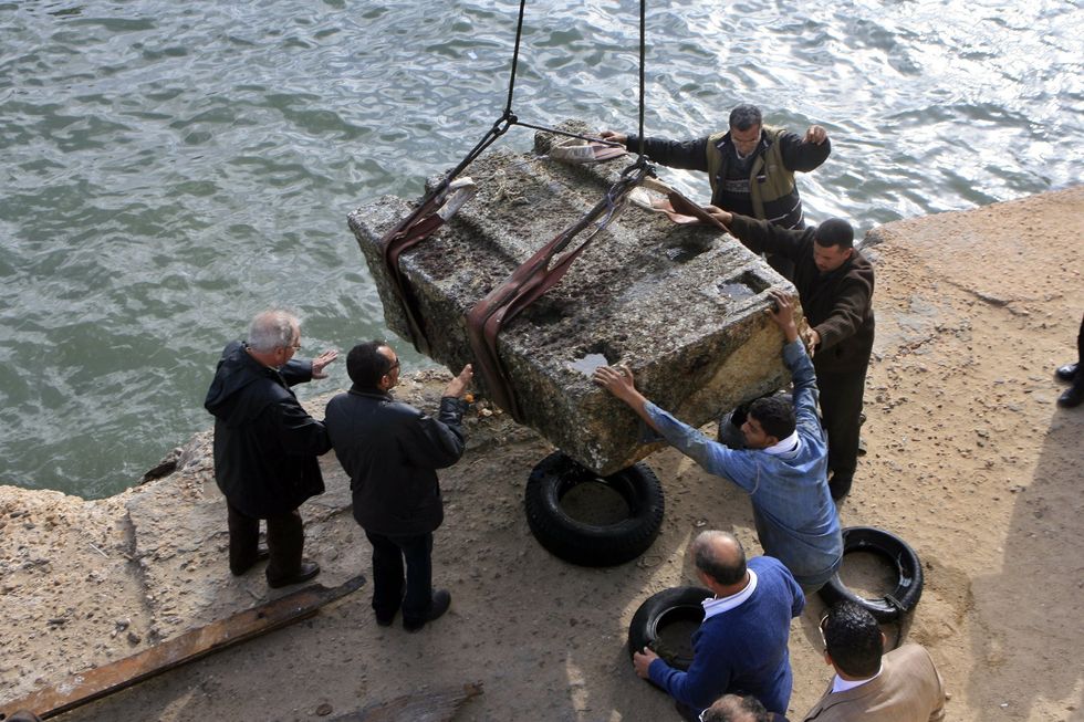 Men lifting large stone from the sea