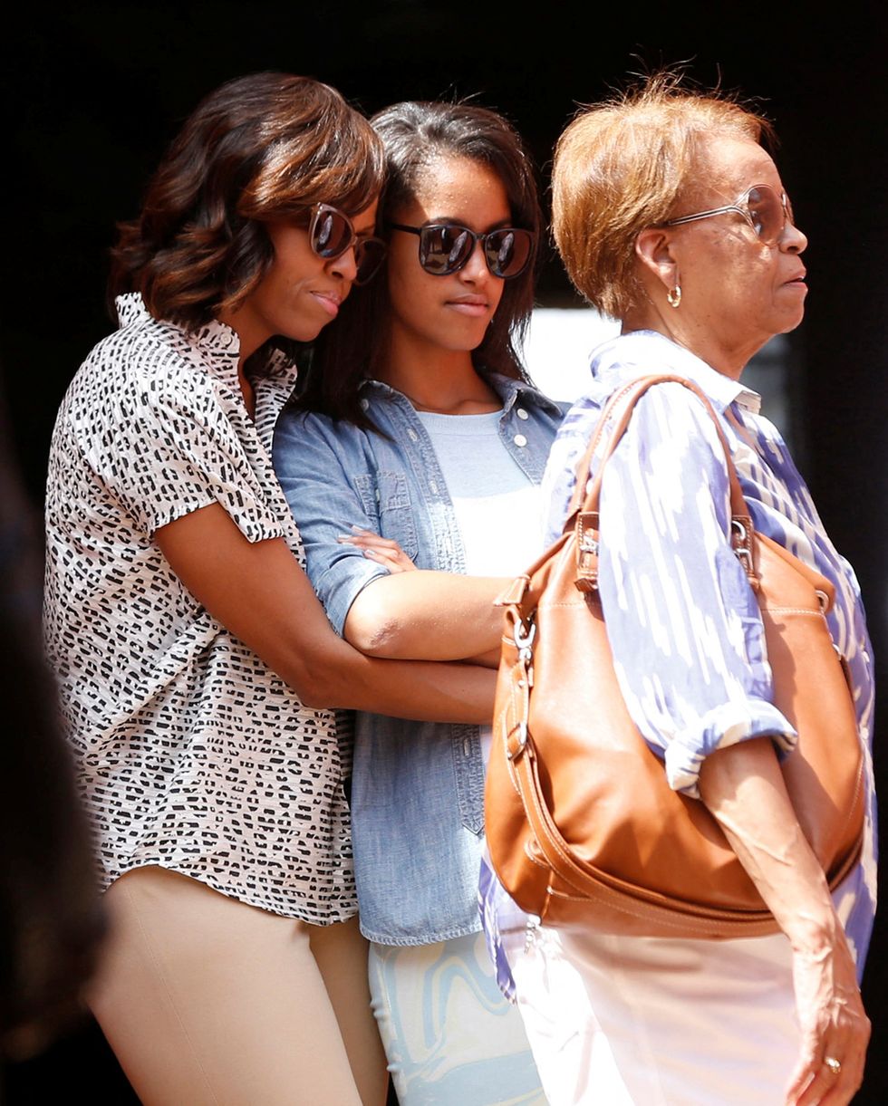 Michelle Obama hugs her daughter Malia alongside Marian Robinson, Michelle Obama's mother, as they visit the Maison Des Ecslaves