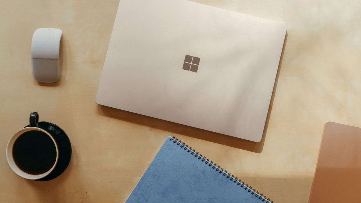 microsoft surface laptop lying on a wooden table with the surface logo showing prominently