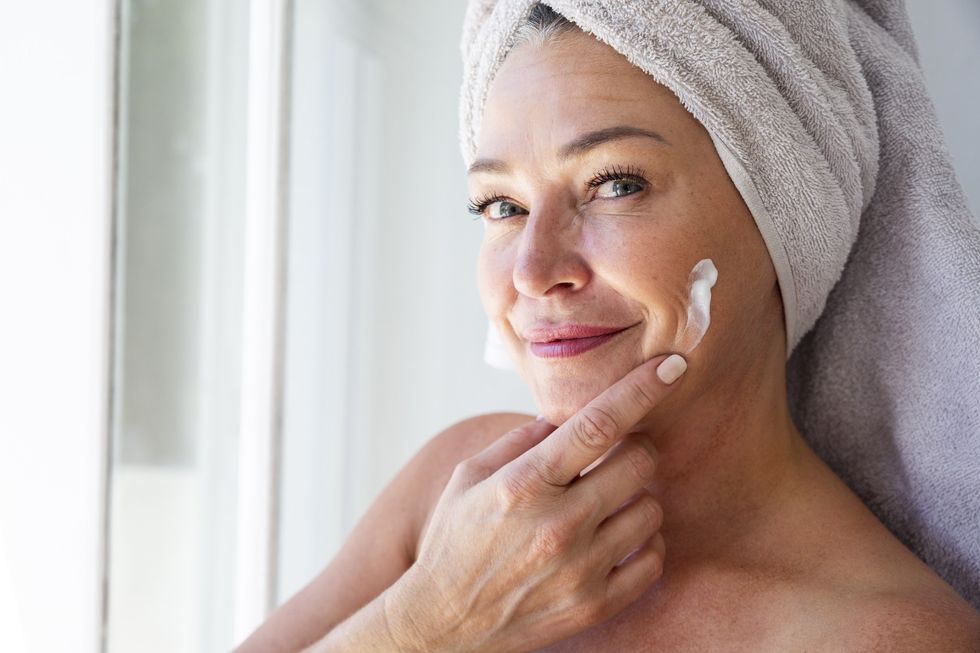 Middle-aged woman applying moisturiser