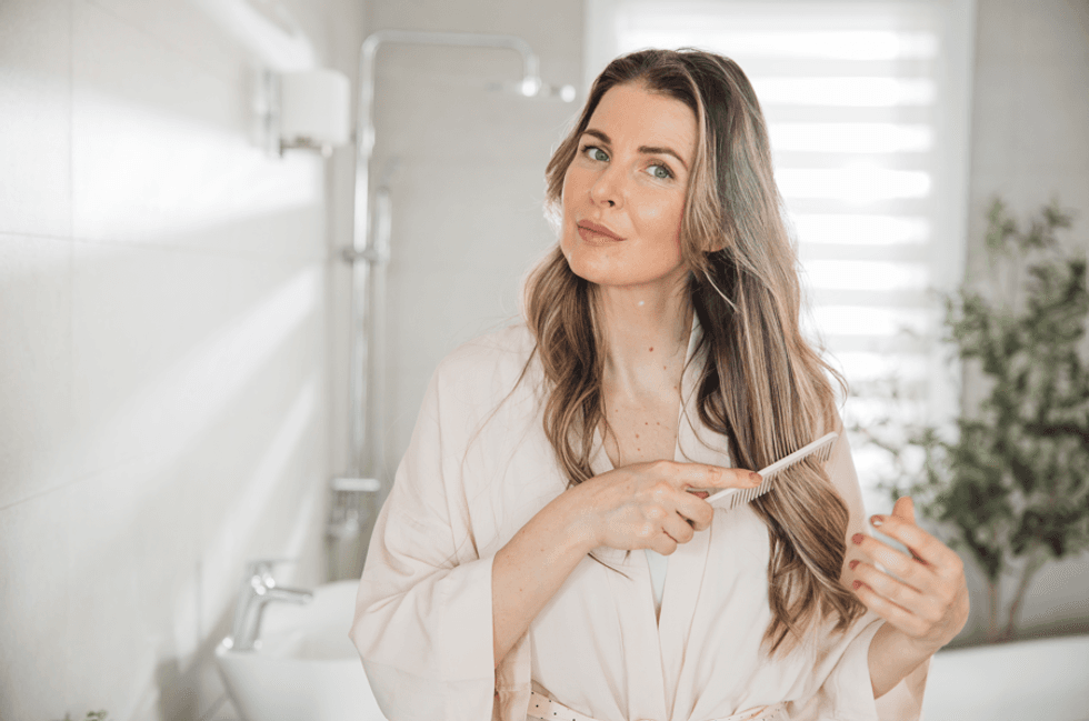Middle-aged woman brushing hair in mirror