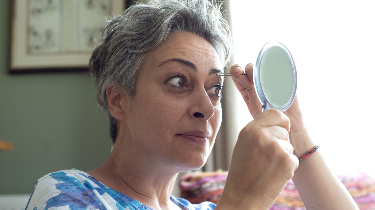 Middle-aged woman plucking her eyebrows