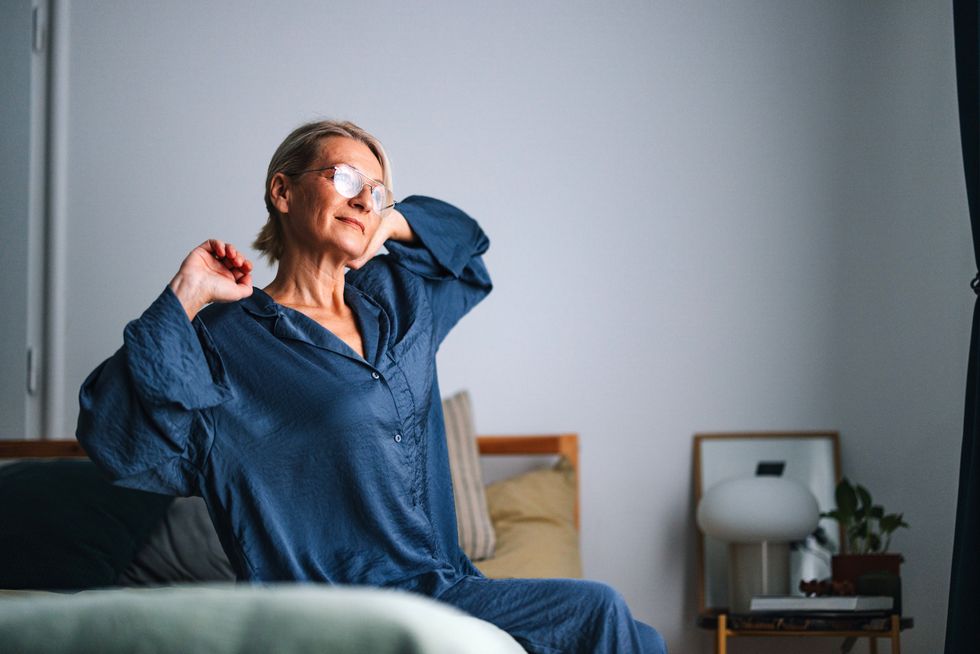 Middle aged woman stretching on bed