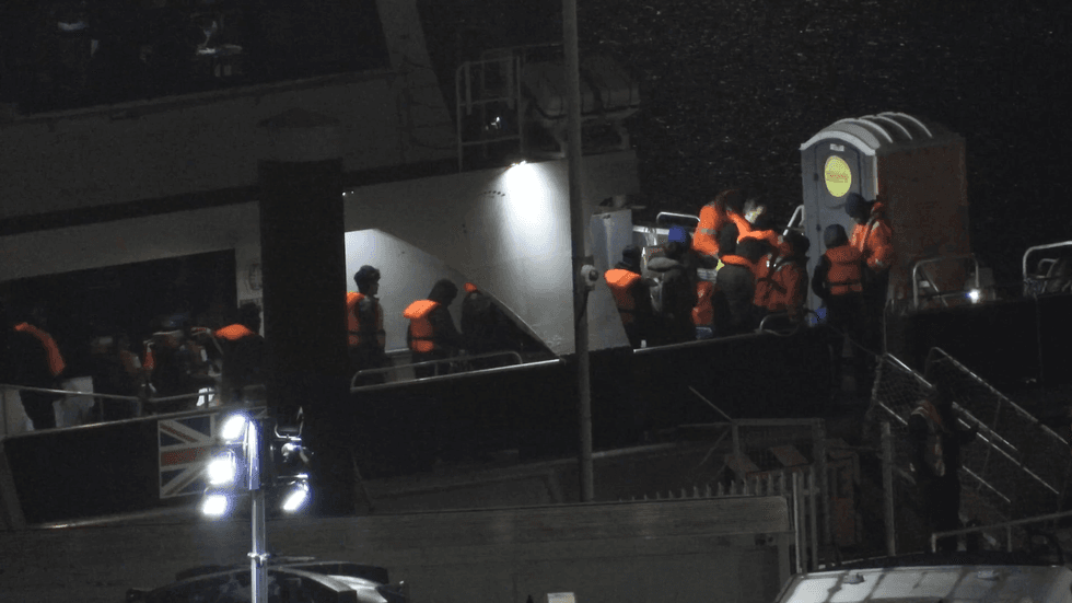 Migrantes chegam de um navio da Força de Fronteira