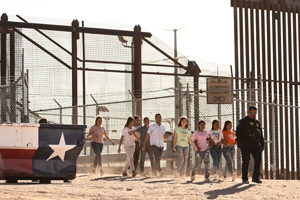 Migrants board vans after waiting along the border wall to surrender to US Customs and Border Protection (CBP) Border Patrol agents