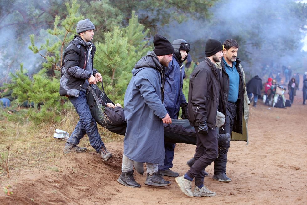 Migrants carry a person on a stretcher as they gather on the Belarusian-Polish border in the Grodno region, Belarus November 8, 2021. Leonid Scheglov/BelTA/Handout via REUTERS ATTENTION EDITORS - THIS IMAGE HAS BEEN SUPPLIED BY A THIRD PARTY. NO RESALES. NO ARCHIVE. MANDATORY CREDIT.