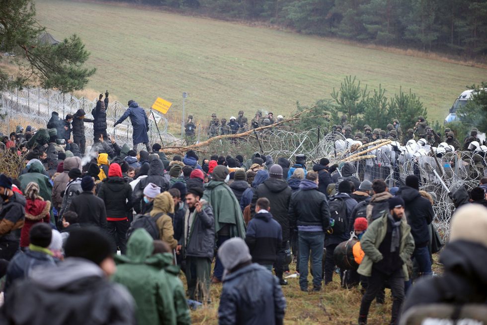 Migrants gather near a barbed wire fence in an attempt to cross the border with Poland in the Grodno region, Belarus November 8, 2021. Leonid Scheglov/BelTA/Handout via REUTERS ATTENTION EDITORS - THIS IMAGE HAS BEEN SUPPLIED BY A THIRD PARTY. NO RESALES. NO ARCHIVE. MANDATORY CREDIT.