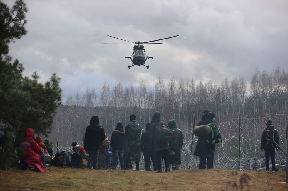 Migrants gather near a barbed wire fence in an attempt to cross the border with Poland in the Grodno region, Belarus November 8, 2021. Leonid Scheglov/BelTA/Handout