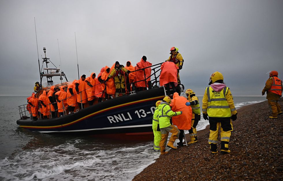 Migrants, picked up at sea attempting to cross the English Channel, are helped ashore from an Royal National Lifeboat Institution (RNLI) lifeboat