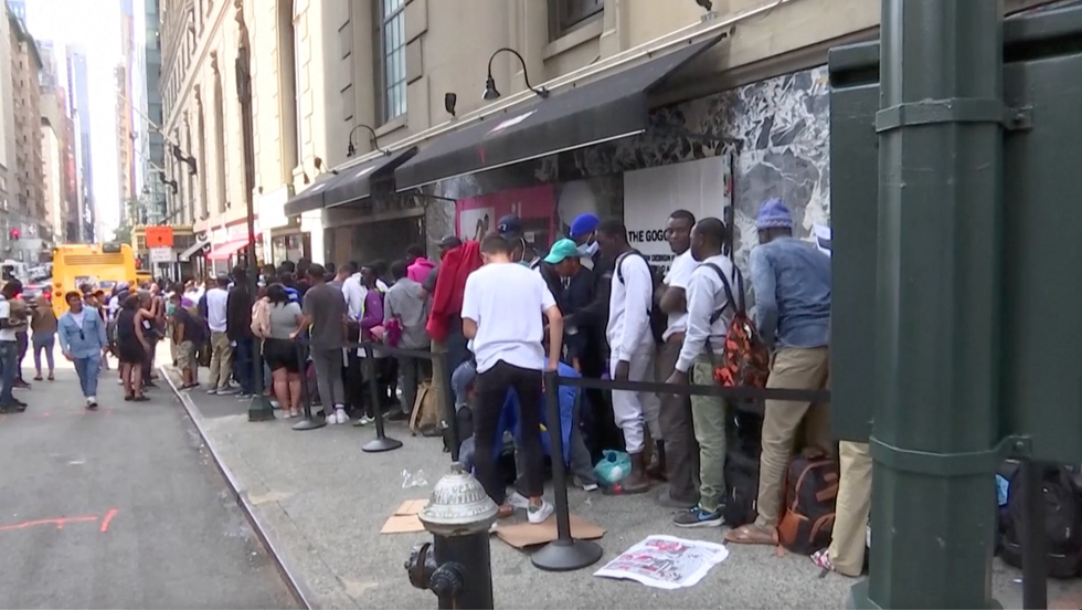 Migrants queue outside of the Roosevelt Hotel in New York in July