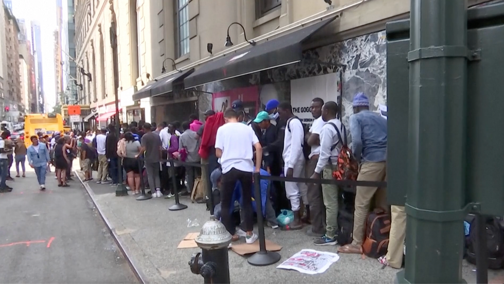 Migrants queue outside of the Roosevelt Hotel in New York