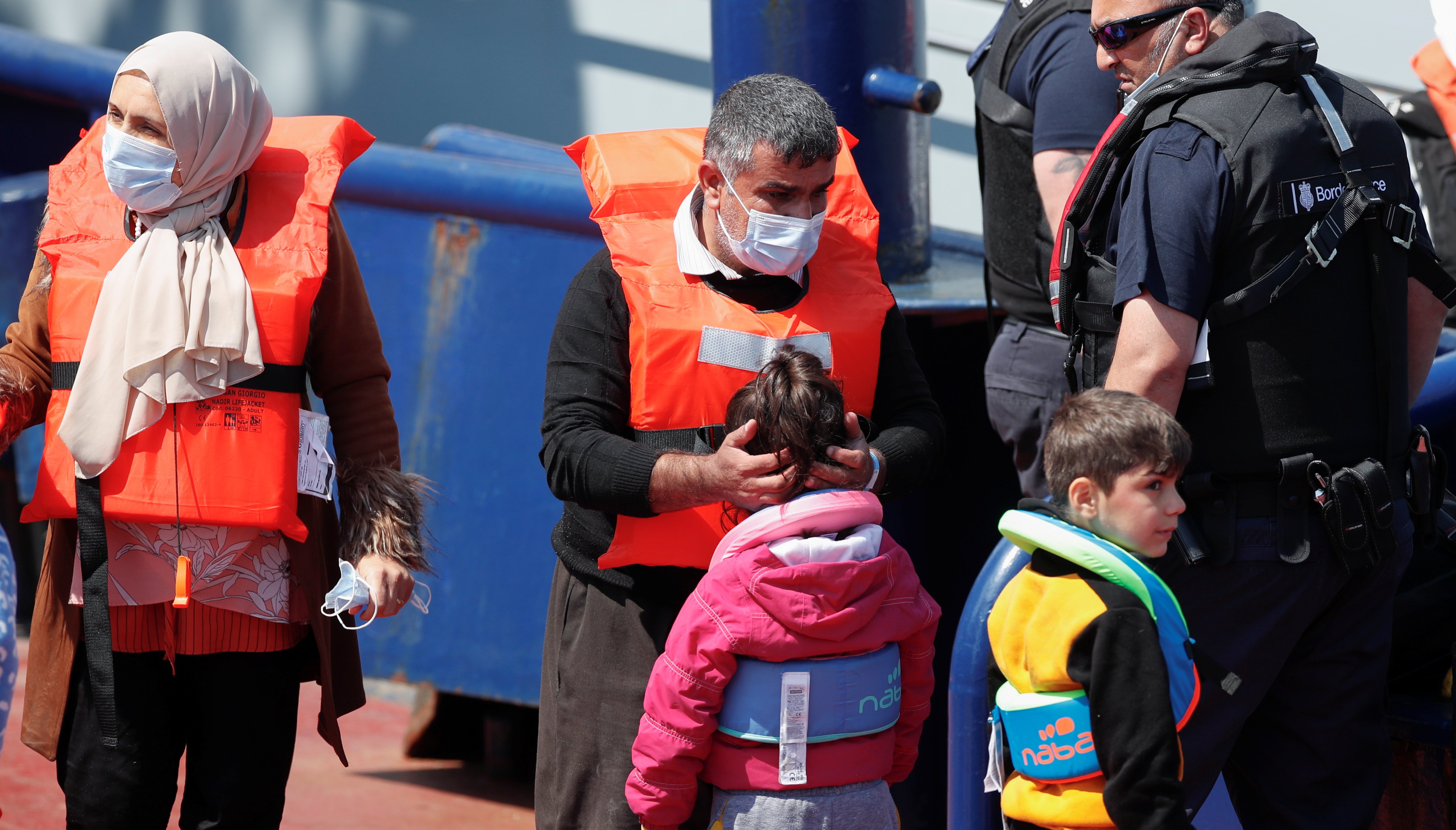 Migrants react as British Border Force staff bring them into Dover harbour