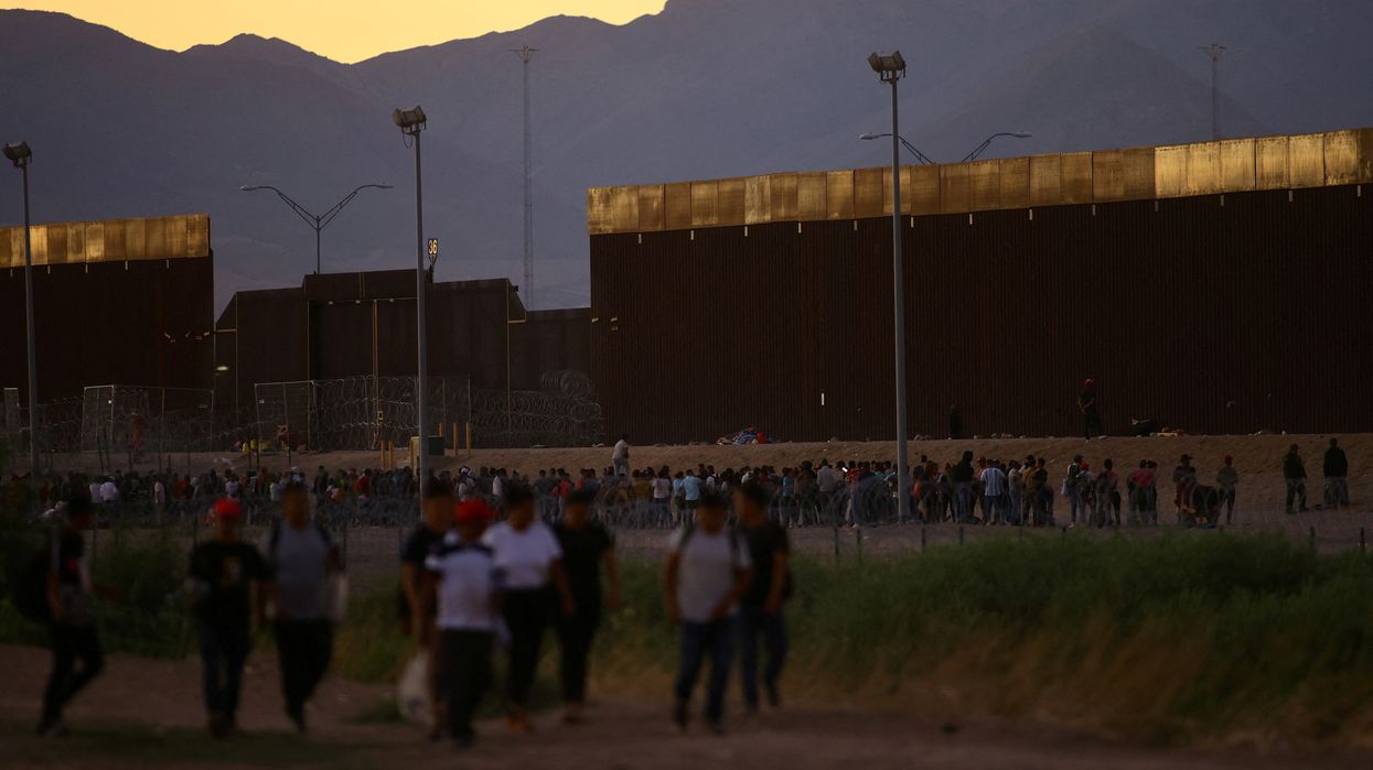 Migrants seeking asylum in the United States gather near a border wall on the banks of the Rio Bravo River