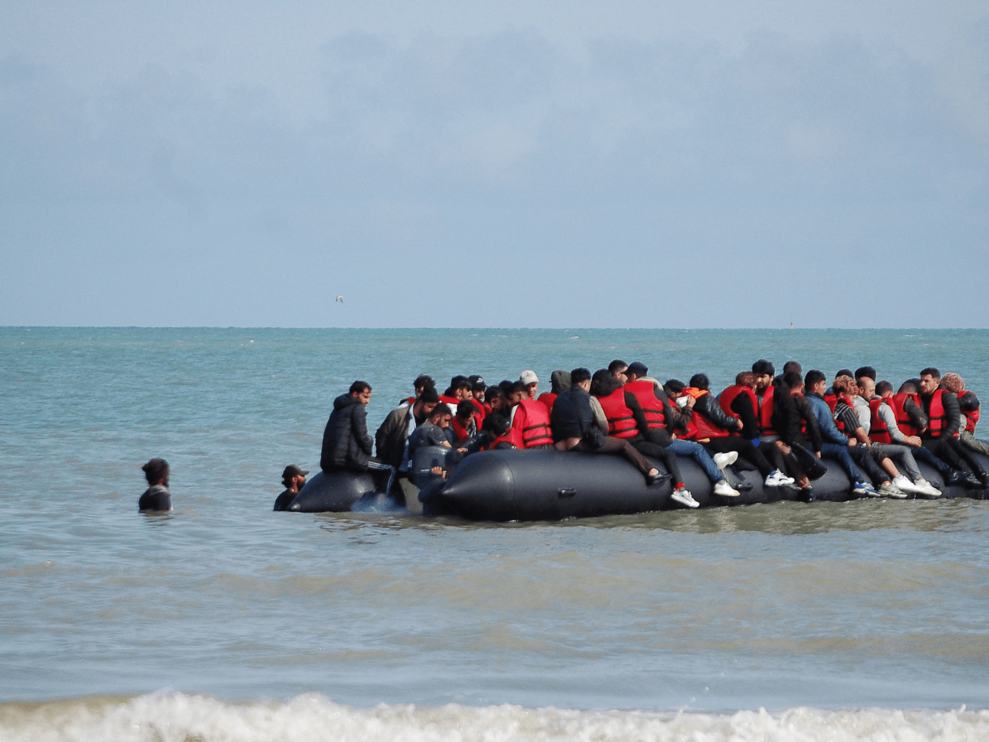 Migrants sit onboard an inflatable boat