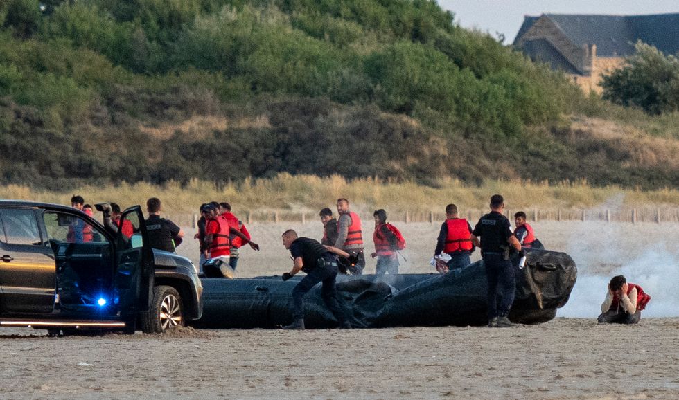 Migrants with women and children make their way down the beach at Gravelines in France this evening.  French Police suddenly appeared and destroyed the engine and punctured the dinghy leaving the migrants to flee - PICTURE BY JOHN McLELLAN - 6.8.22