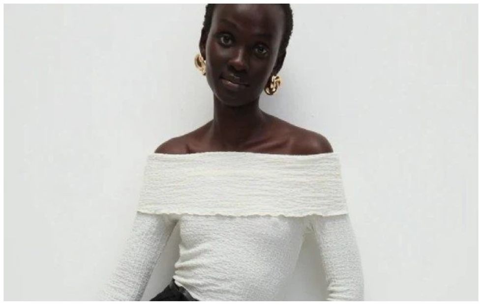 Model depicted wearing white off-shoulder top and black trousers in M&S ad