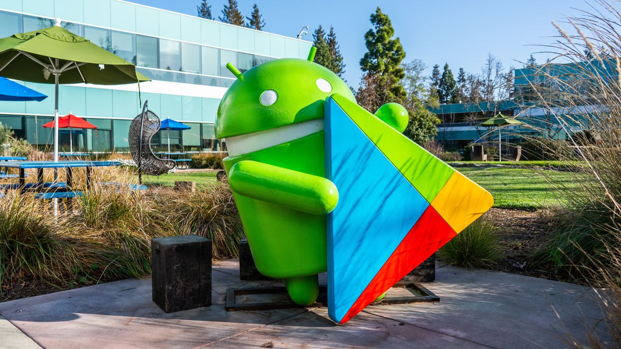 model of the google android mascot pictured holding the logo for the play store in the google campus in california