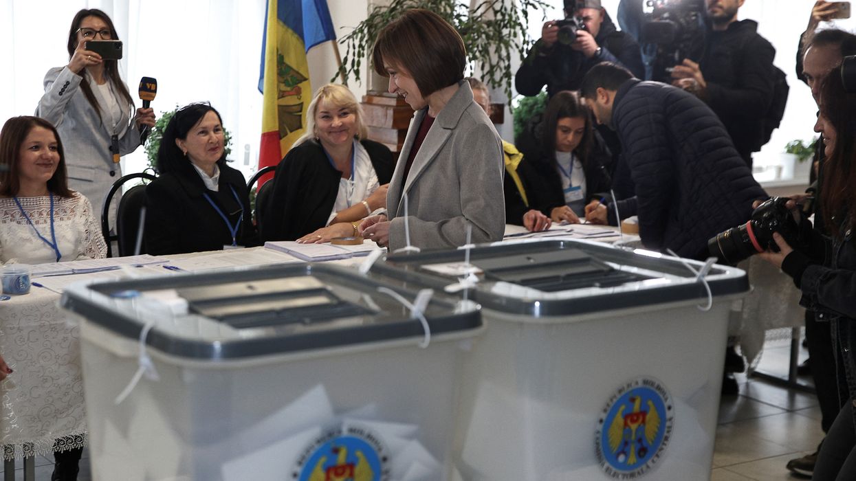 Moldova's incumbent President and presidential candidate Maia Sandu stands in front of members of a local electoral commission at a polling station